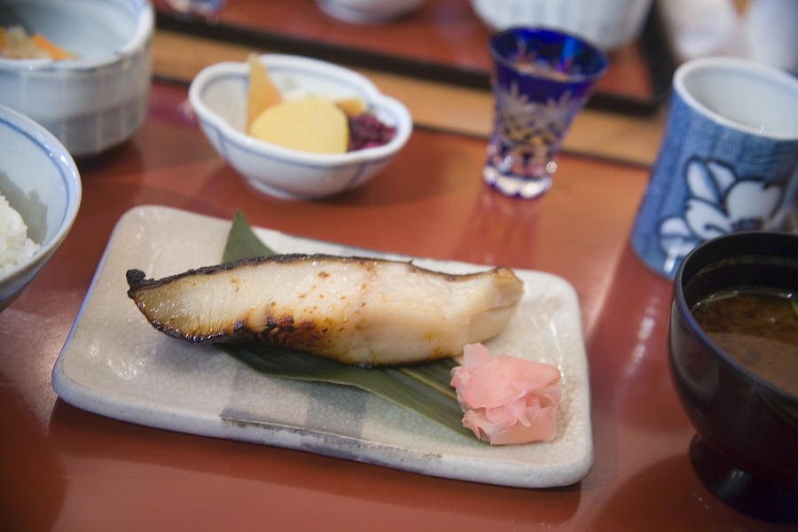 Food on dining table (focus on grilled sablefish in foreground) Photograph by Akira Kaede