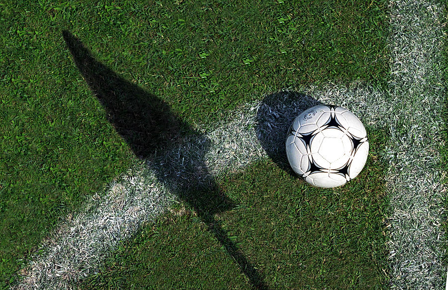 Football on grass by pitch marking and shadow of flag Photograph by Photo and Co