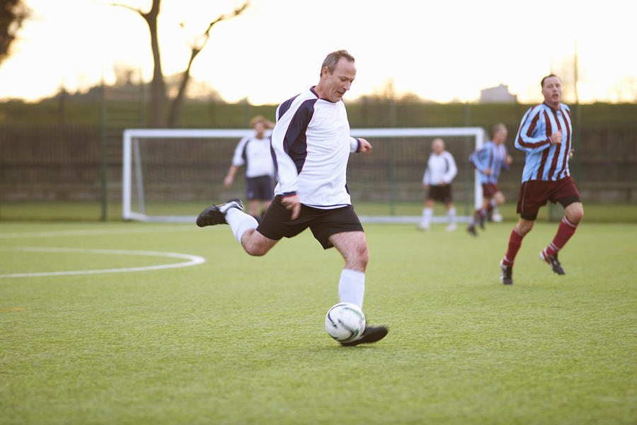 Football player kicking ball Photograph by Peter Muller