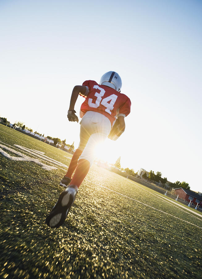Football player running on field with football Photograph by Tetra Images - Erik Isakson