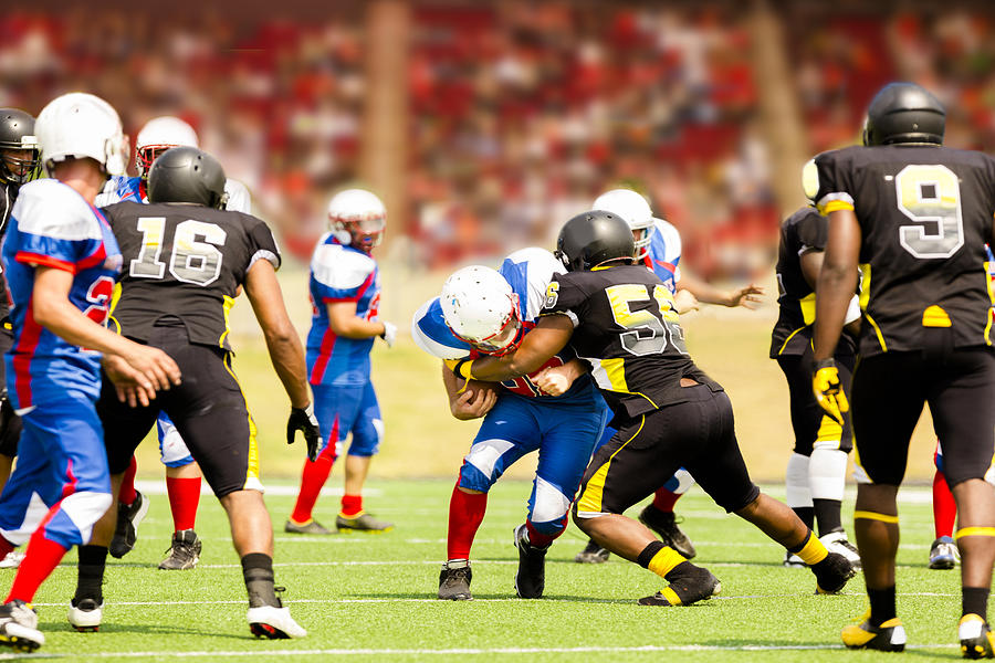 Football teams running back carries ball. Defenders. Stadium fans. Field. Photograph by Fstop123