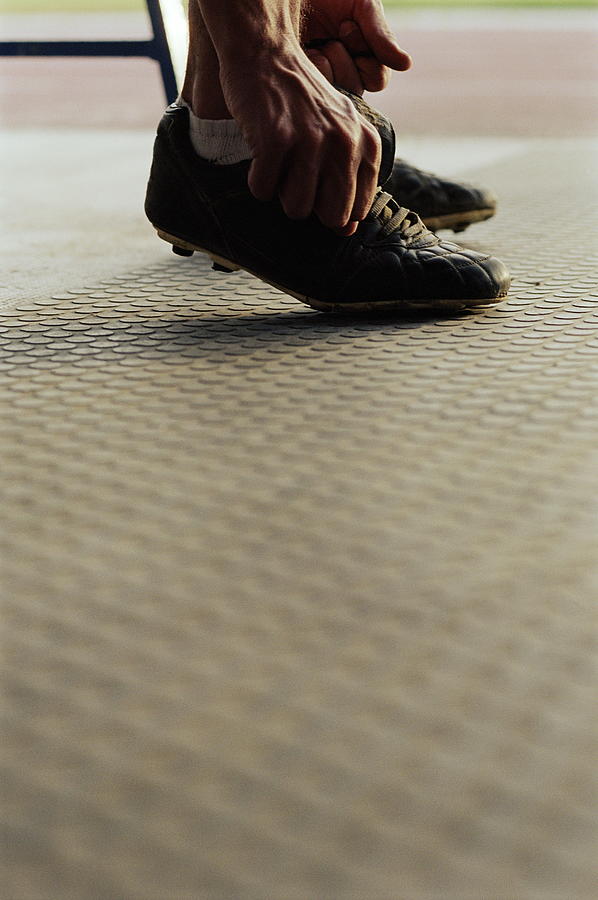 Footballer tying laces, low section Photograph by David Leahy