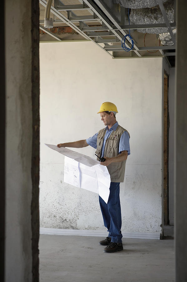 Foreman Stands in a Building Site Examining a Blueprint Photograph by Digital Vision.