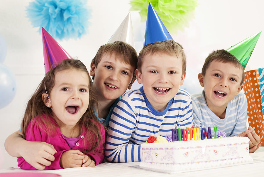 Four happy children celebrating a birthday Photograph by Vitapix
