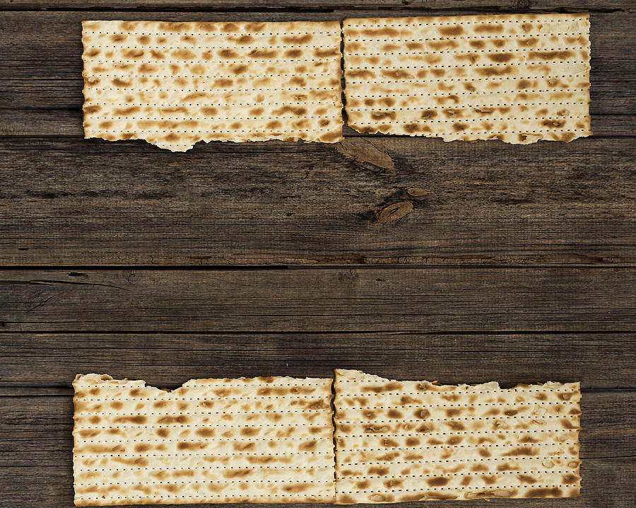 Four pieces of matzah on a vintage wood background with copy space or text space. Photograph by Vlad Fishman