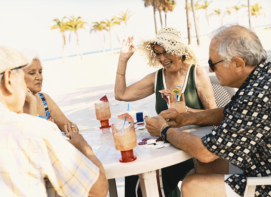 Four Senior People Playing Poker on the Beach Photograph by Digital Vision.