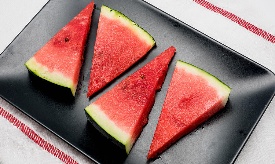 Four slices of watermelon on black dish Photograph by Shootdiem