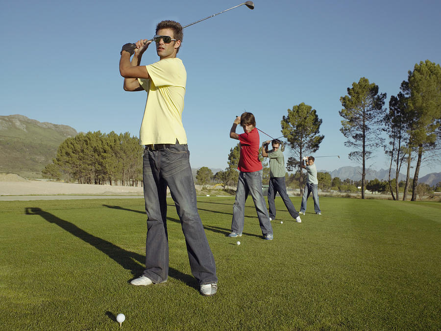 Four Young Men Playing Golf on a Golf Course Photograph by Digital Vision.