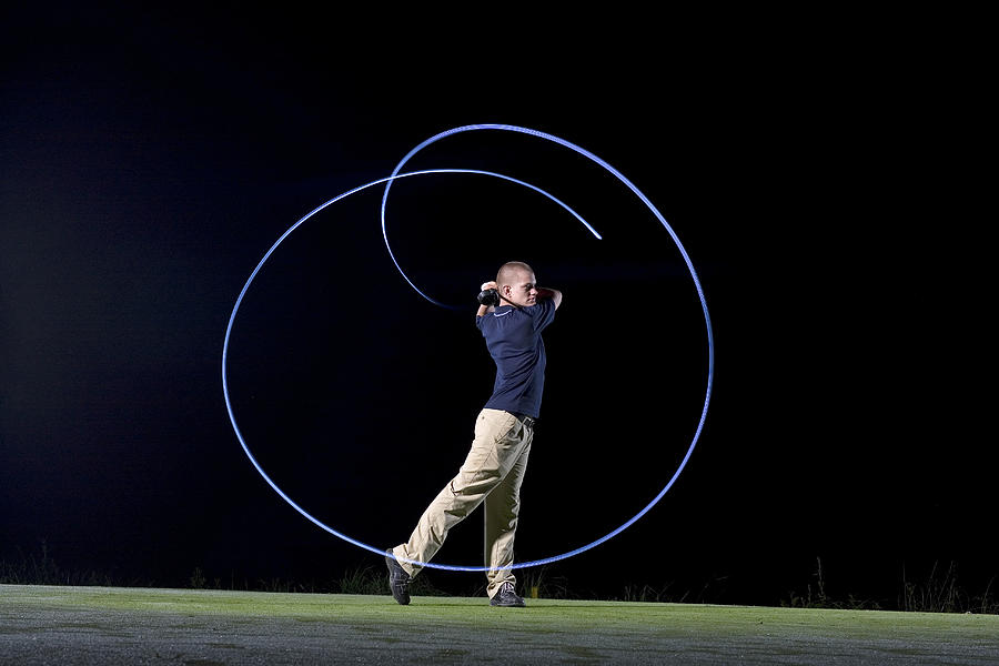 France, Dordogne, golfer swinging club on golf course at night, blurred motion Photograph by Photo and Co