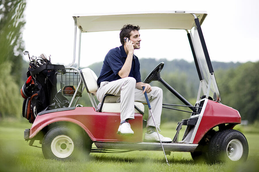 France, Dordogne, male golfer using mobile phone in golf cart Photograph by Photo and Co