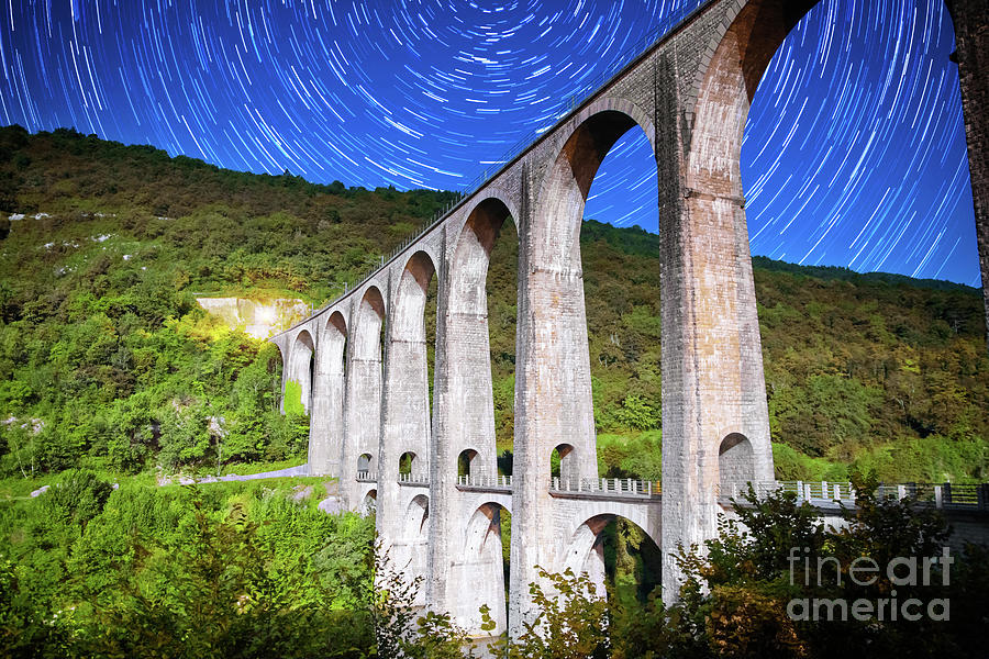 French old stone viaduct arch bridge architecture under moonlight with star trail in summer sky nigh Photograph by Gregory DUBUS
