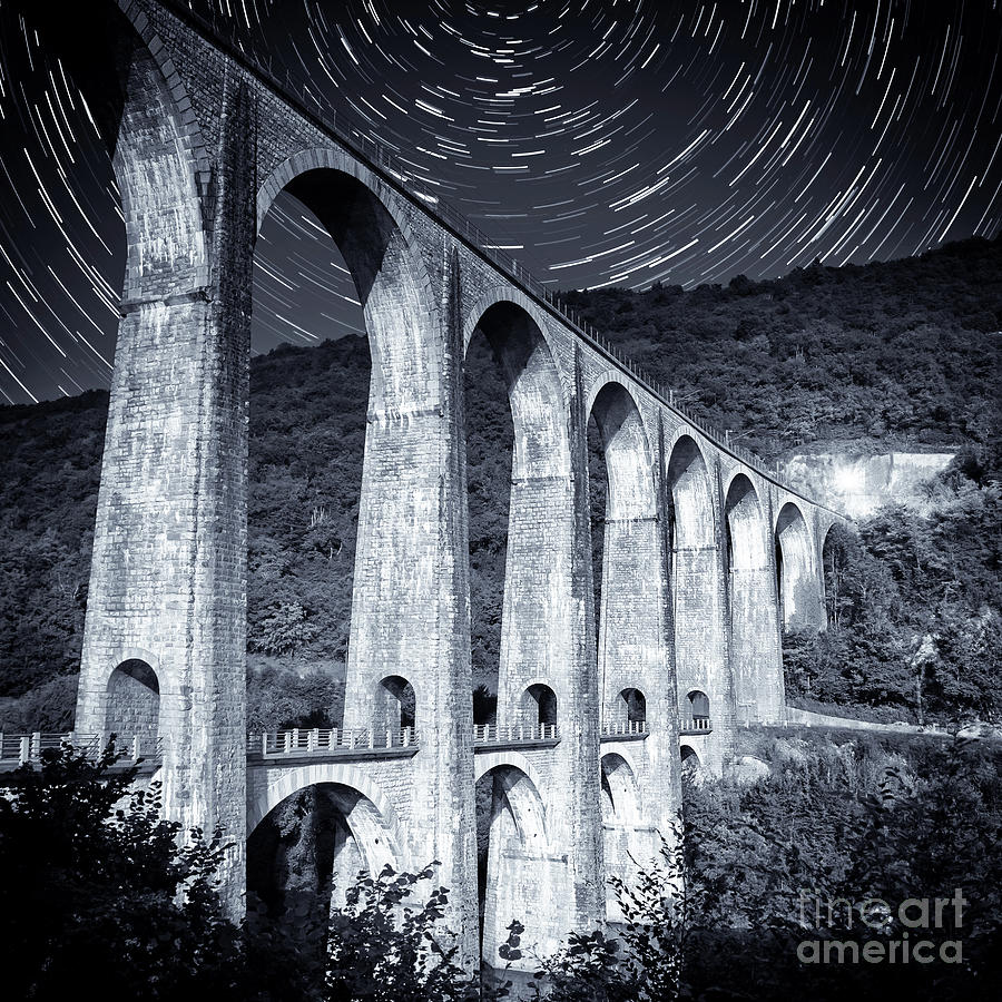 French old stone viaduct architecture under moonlight with star trails monochrome Photograph by Gregory DUBUS
