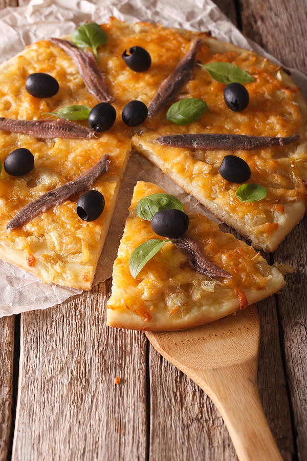 French Pissaladiere with anchovies and onions close-up. Vertical Photograph by Alleko