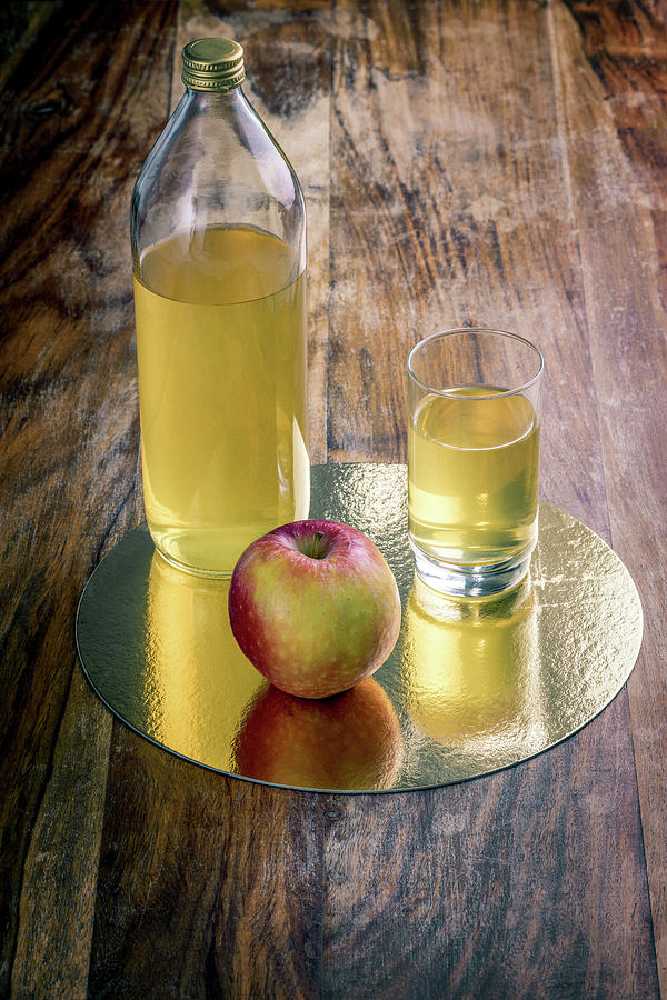 Fresh apple juice and red apple on a rustic wooden table Photograph by Benoit Bruchez