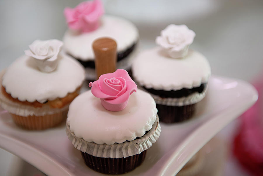 Fresh delicious cupcakes with white sugar garnish and pink sweet flower on top Photograph by Michalakis Ppalis