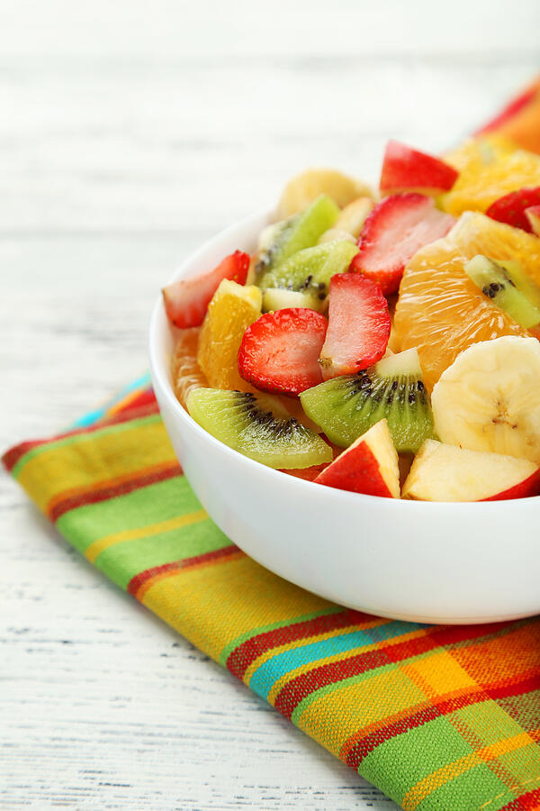 Fresh fruit salad on white wooden background Photograph by 5second