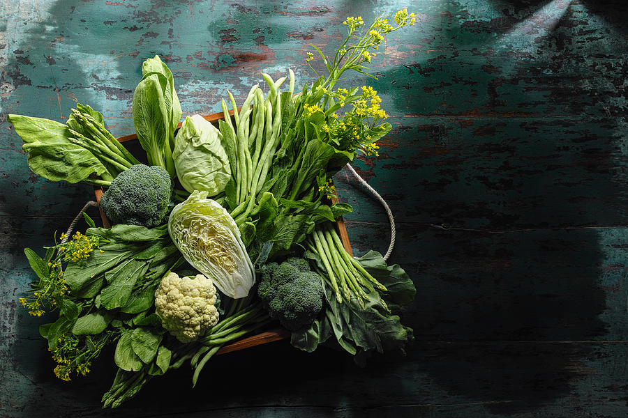 Fresh green leaf vegetables in an old wooden crate on an old wooden turquoise table. Photograph by Enviromantic