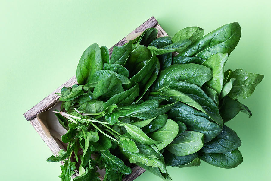 Fresh organic spinach in wooden crate on green background Photograph by Istetiana
