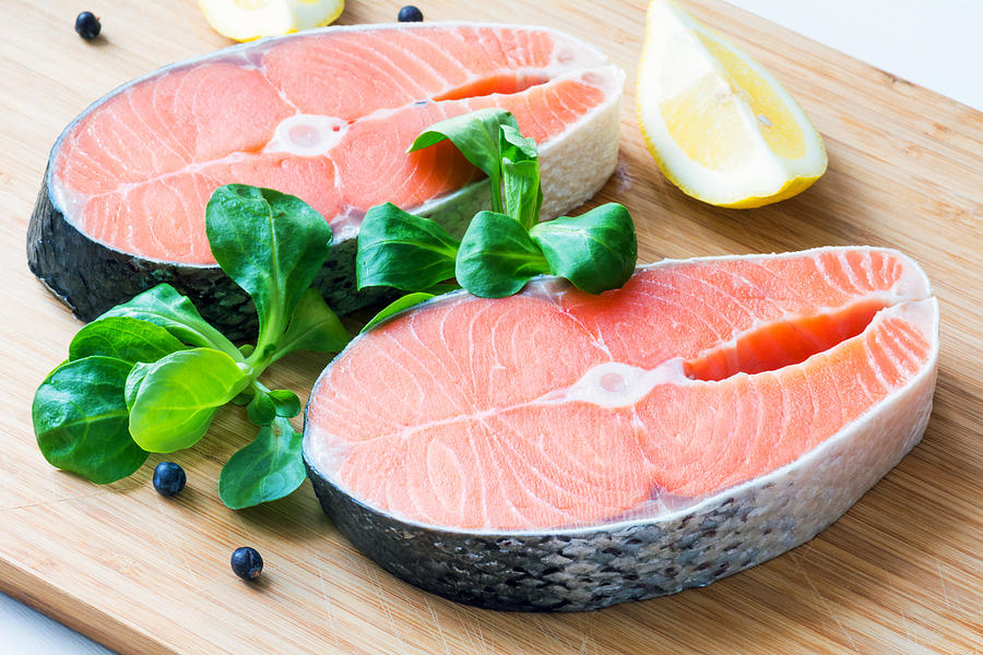 Fresh raw salmon steaks on wooden board Photograph by Arx0nt