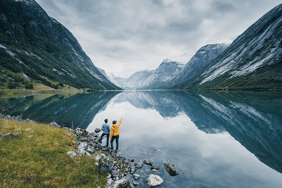 Friends admiring the view on the banks of a norwegian fjord, Norway Photograph by © Marco Bottigelli