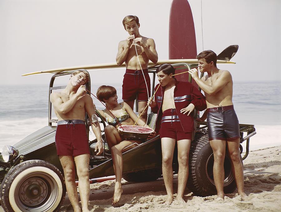 Friends drinking juice from watermelon on beach Photograph by Tom Kelley Archive