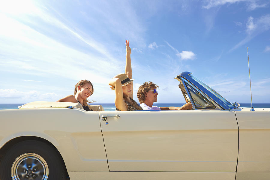 Friends driving convertible under blue sky Photograph by Colin Anderson Productions pty ltd