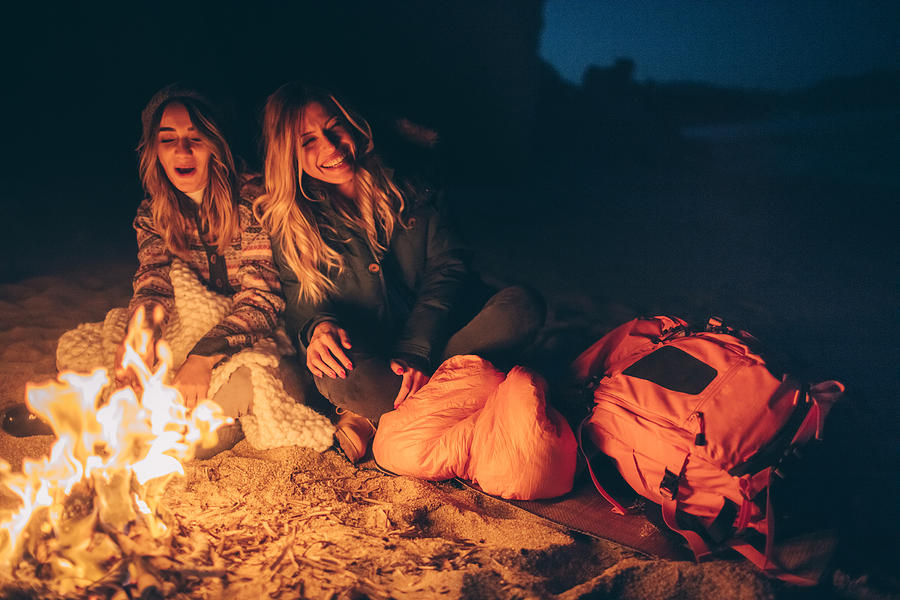 Friends enjoy evening on the beach by the log fire Photograph by AleksandarNakic