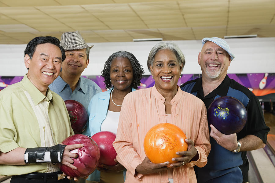 Friends holding bowling balls in bowling alley Photograph by Jon Feingersh Photography Inc