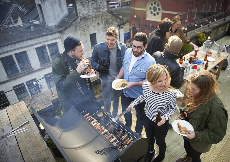 Friends in roof garden sharing barbecued food. Photograph by Mike Harrington