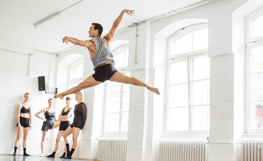 Friends looking at male ballet dancer in mid-air Photograph by Luis Alvarez