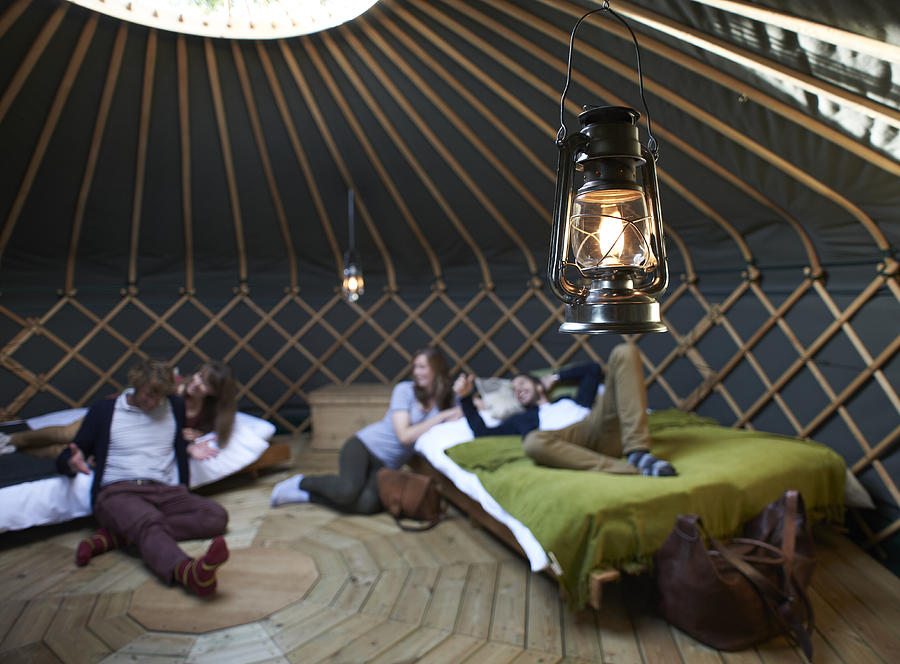 Friends lounging around beds inside yurt. Photograph by Mike Harrington