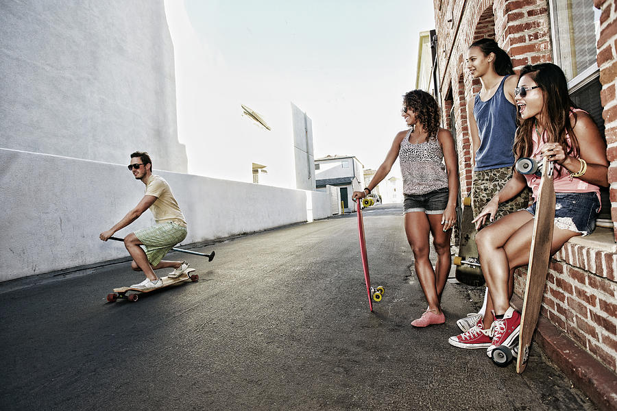 Friends riding longboards on city street Photograph by Peathegee Inc