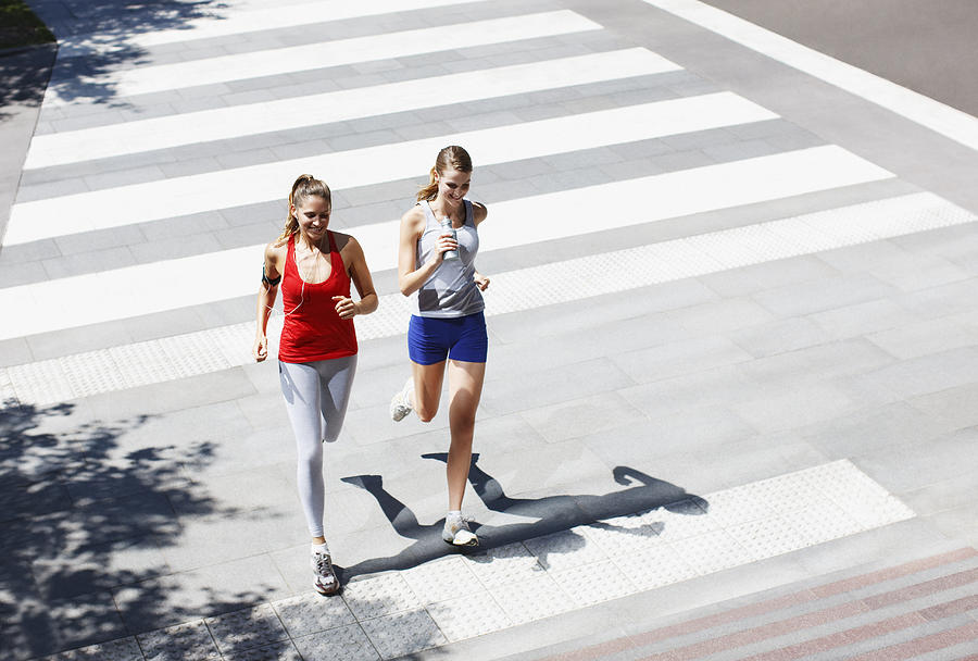 Friends running across urban crosswalk Photograph by Paul Bradbury