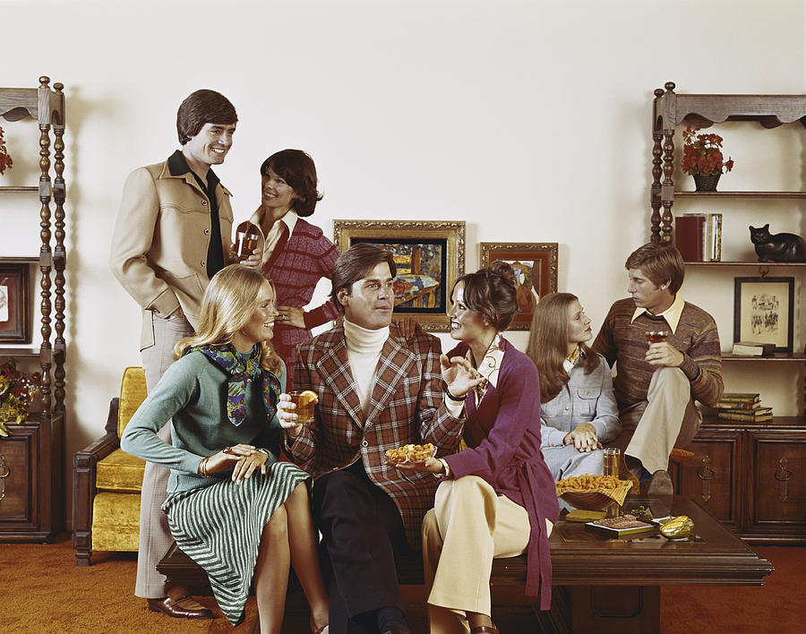 Friends sitting in living room having drinks, smiling Photograph by Tom Kelley Archive
