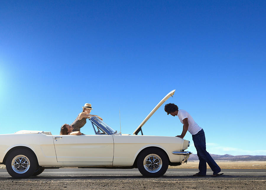 Friends stranded with broken down convertible on remote road Photograph by Colin Anderson Productions pty ltd
