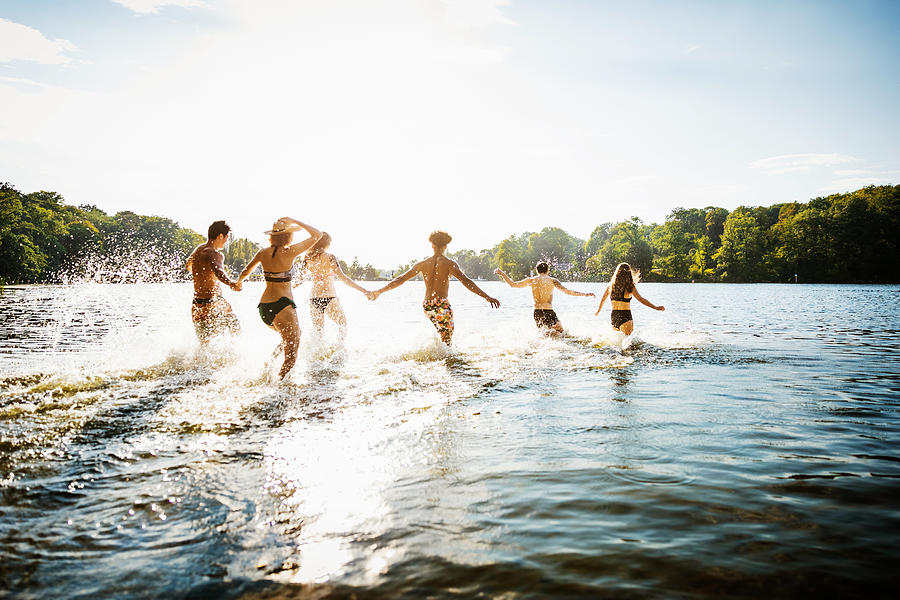 Friends Wading Into Lake In Summer Sun Photograph by Hinterhaus Productions