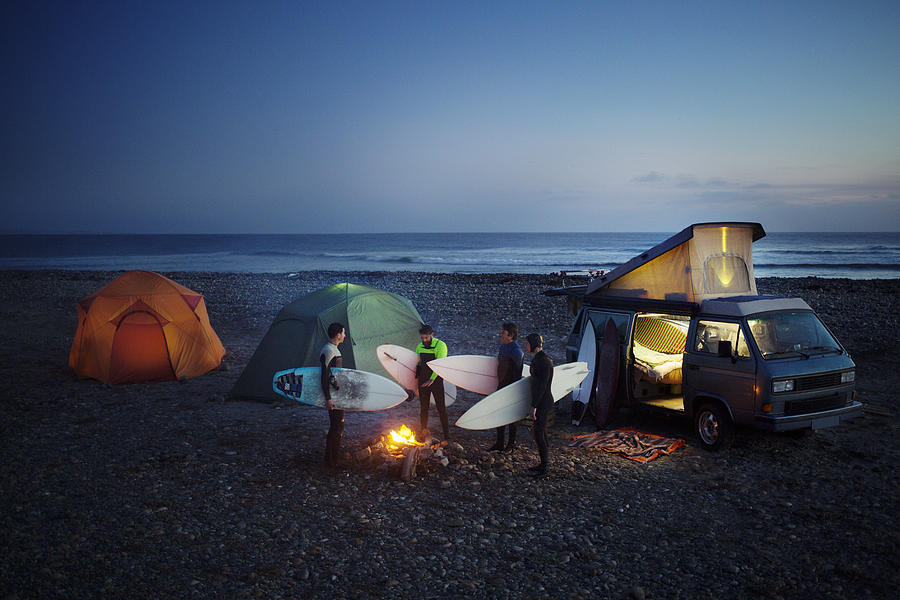 Friends with surfboard camping at beach against sky Photograph by Cavan Images