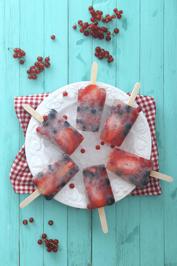 Fruits ice lolly with fresh berries on a plate Photograph by Westend61