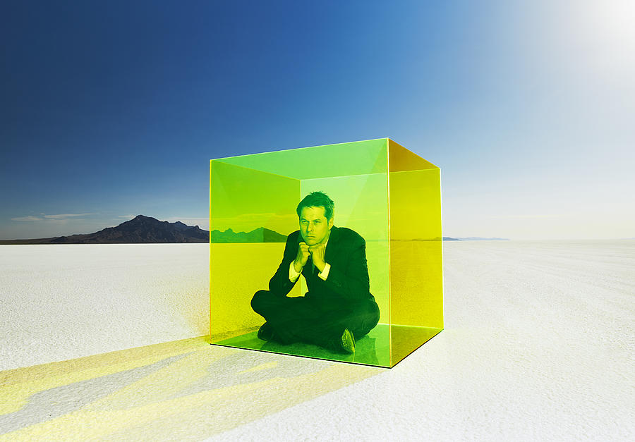 Frustrated businessman in box in desert. Photograph by Andy Ryan