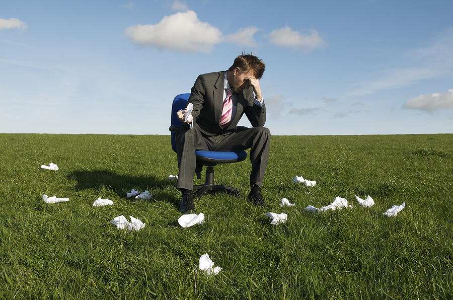 Frustrated Businessman Sitting in Meadow with Rejected Crumpled Paper Photograph by PeskyMonkey