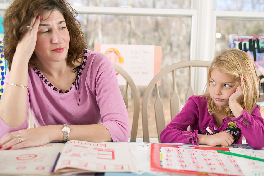 Frustrated mother helping bored daughter with homework Photograph by Image Source
