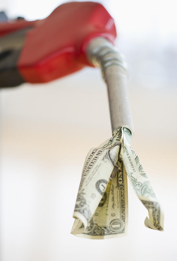 Fuel nozzle with dollar bill Photograph by Tetra Images