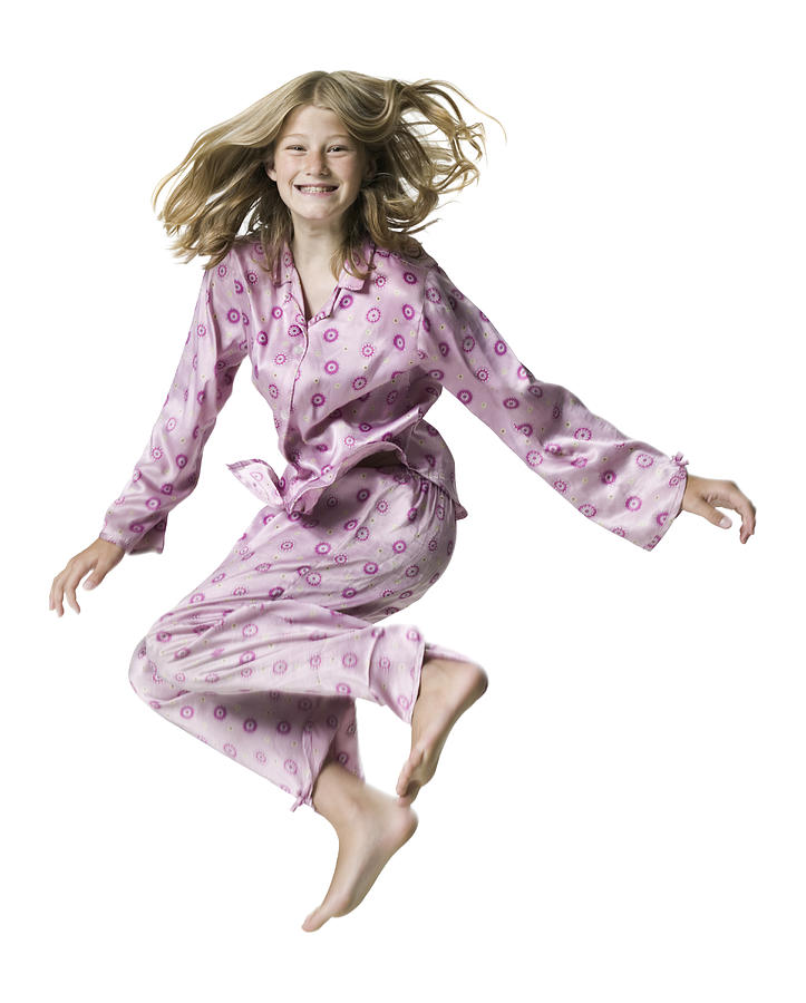 Full Body Portrait Of A Teenage Female In Pink Pajamas As She Jumps Up In The Air Photograph by Photodisc