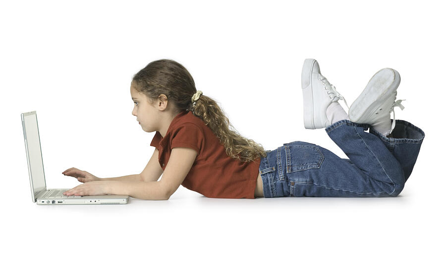 Full Body Shot Of A Female Child As She Lays Down And Uses A Laptop Computer Photograph by Photodisc