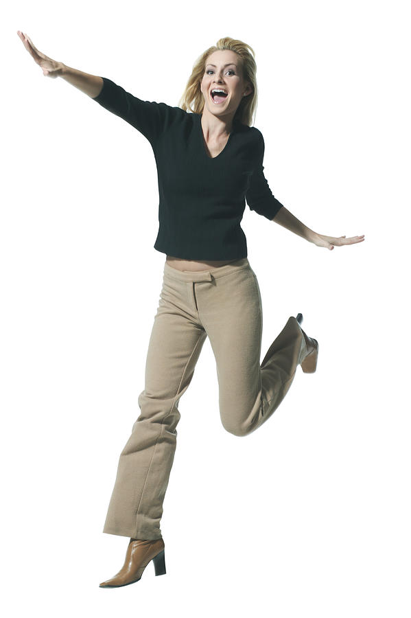 Full Body Shot Of A Young Adult Blonde Female In A Black Sweater As She Playfully Jumps Through The Air Photograph by Photodisc