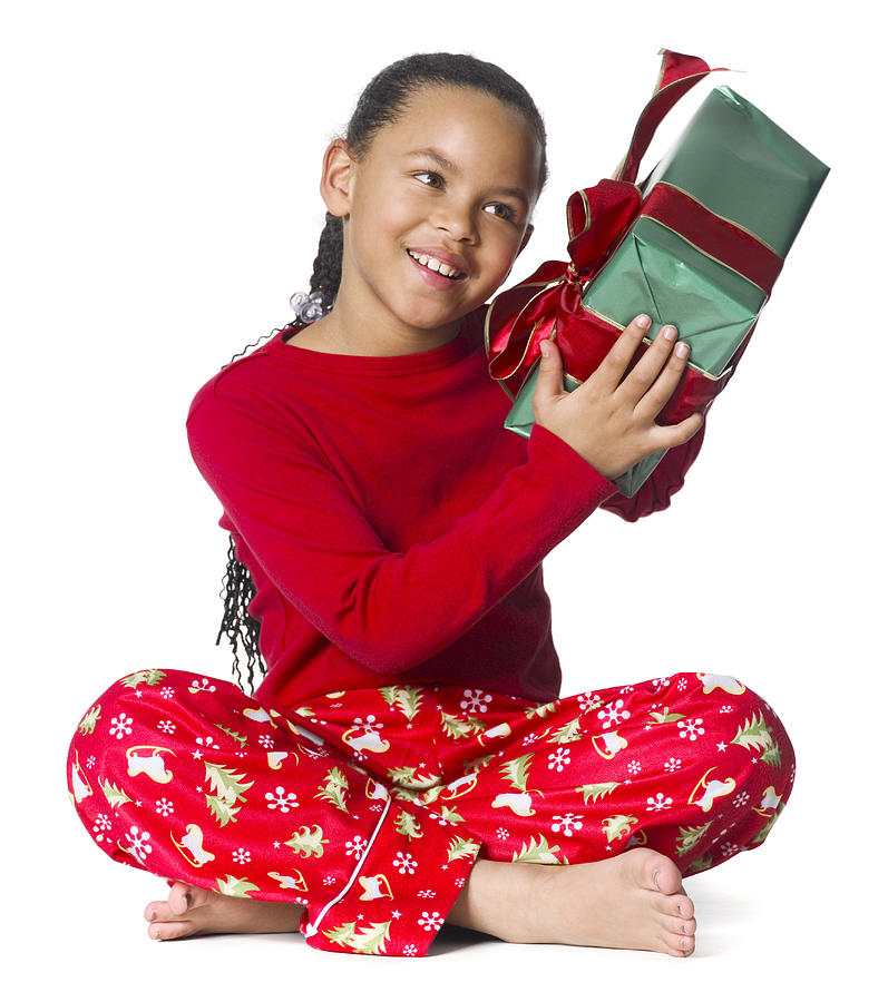 Full Body Shot Of A Young Female Child In Her Pajamas As She Shakes A Wrapped Package Photograph by Photodisc