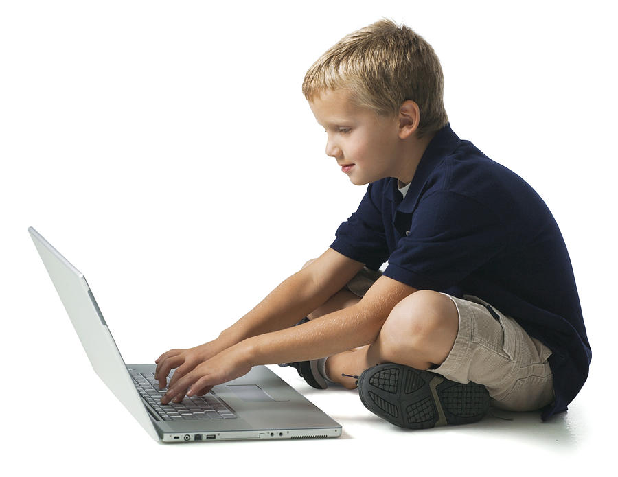 Full Body Shot Of A Young Male Child As He Sits And Works On A Laptop Computer Photograph by Photodisc
