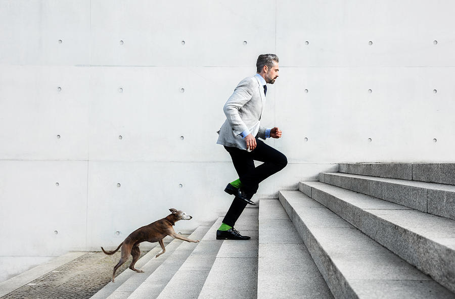 Full length of businessmen running on steps with dog Photograph by Nikada