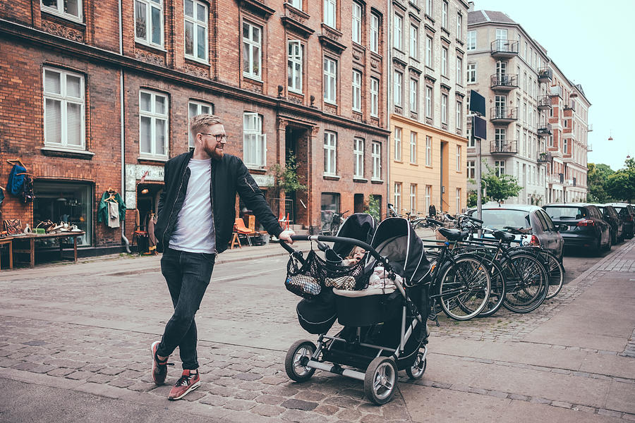 Full length of father standing by baby carriage on street in city Photograph by Maskot