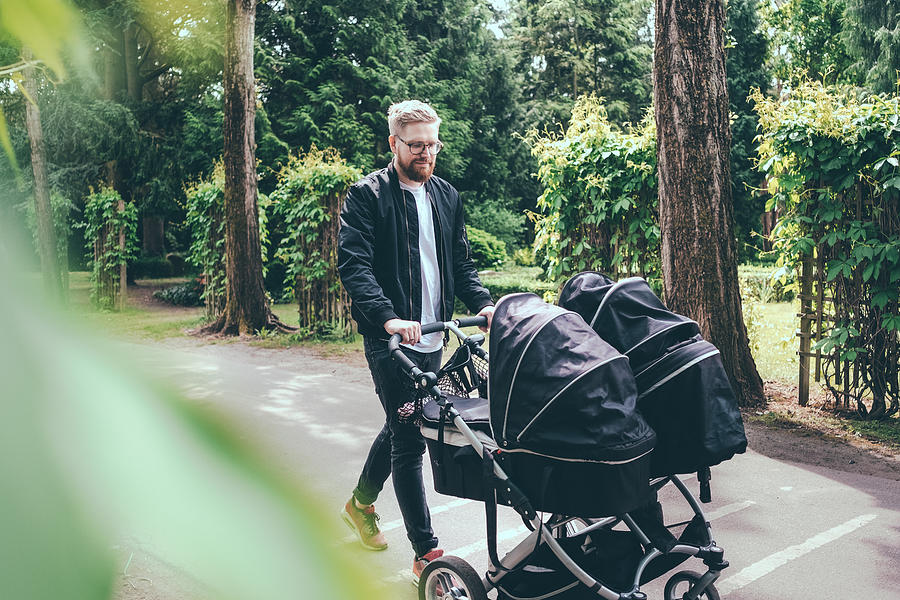 Full length of man pushing baby carriage on footpath Photograph by Maskot